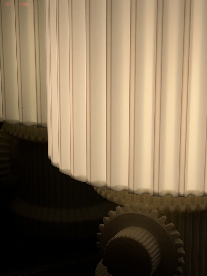 Close view of the Gear Lamp shade edge and gear-shaped control in warm light