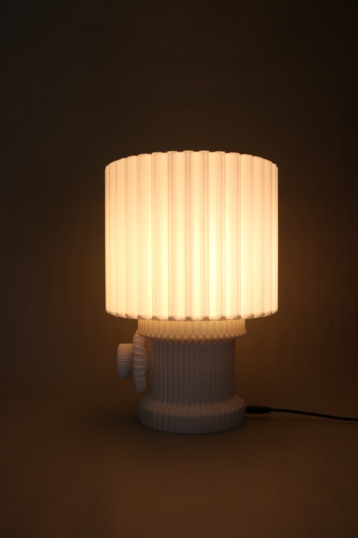 Gear Lamp glowing on a tabletop against a dark studio background