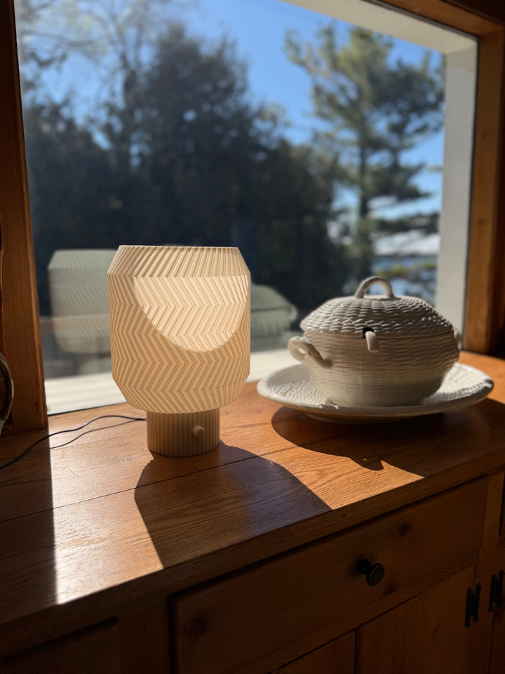 Origami Lamp glowing beside a ceramic teapot on a sunlit wooden cabinet