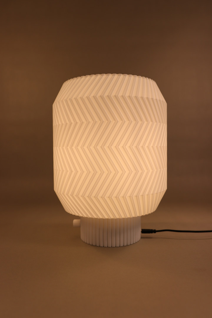 Origami Lamp glowing against a warm brown studio background