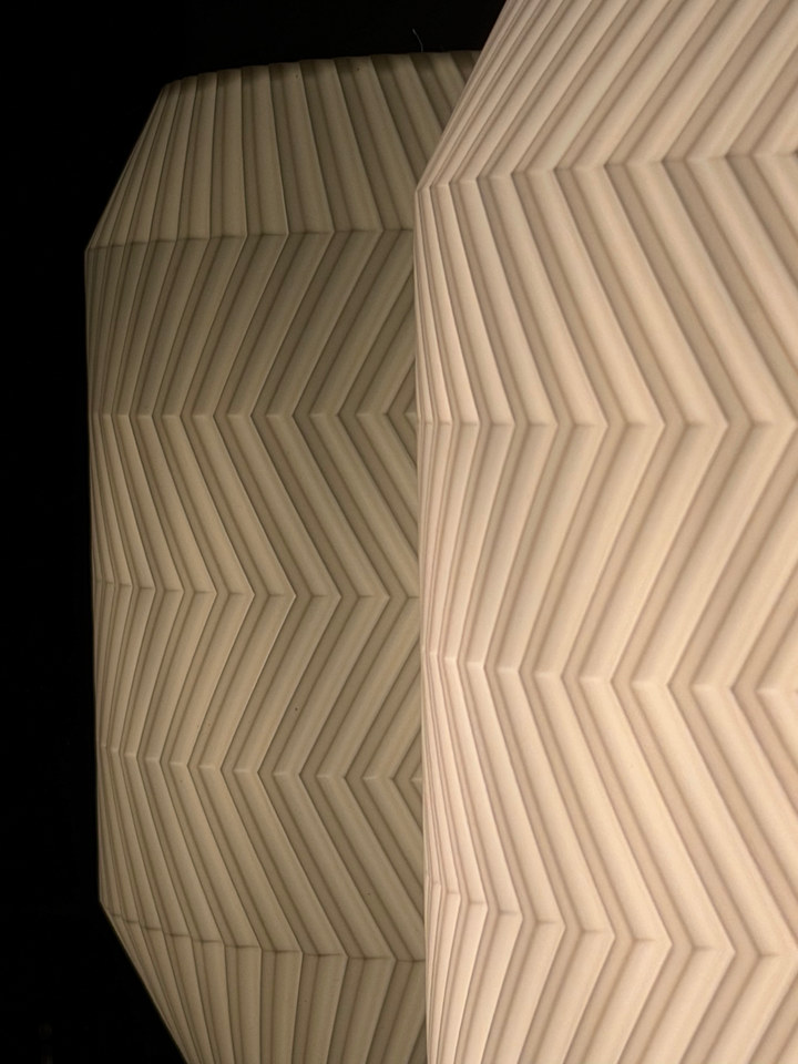 Close view of the folded-chevron shade reflected on a glossy black surface
