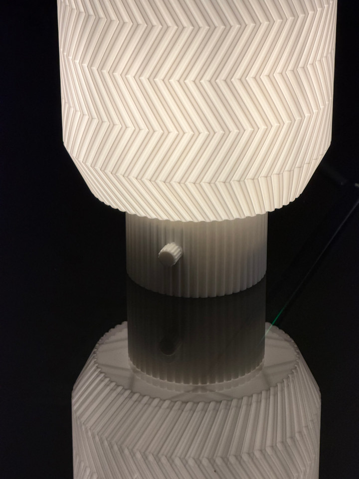 Close view of the Origami Lamp base reflected on a glossy black surface