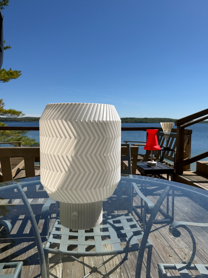 Origami Lamp outdoors on a glass patio table beneath a blue sky