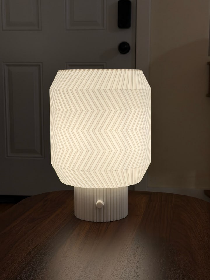 Origami Lamp glowing on a wooden table in front of a paneled door