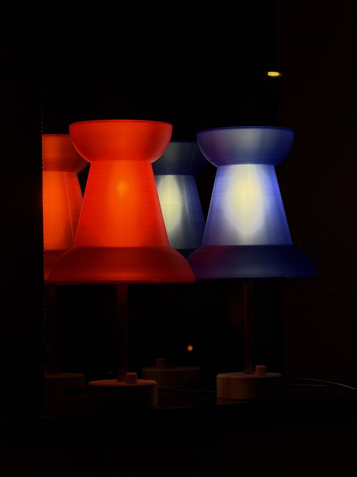 Red and blue Pushpin Lamps reflected on a glossy black surface