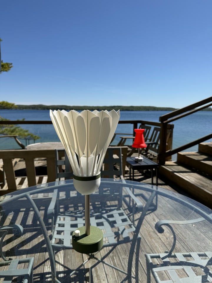 Shuttlecock Lamp on a glass patio table overlooking a lake