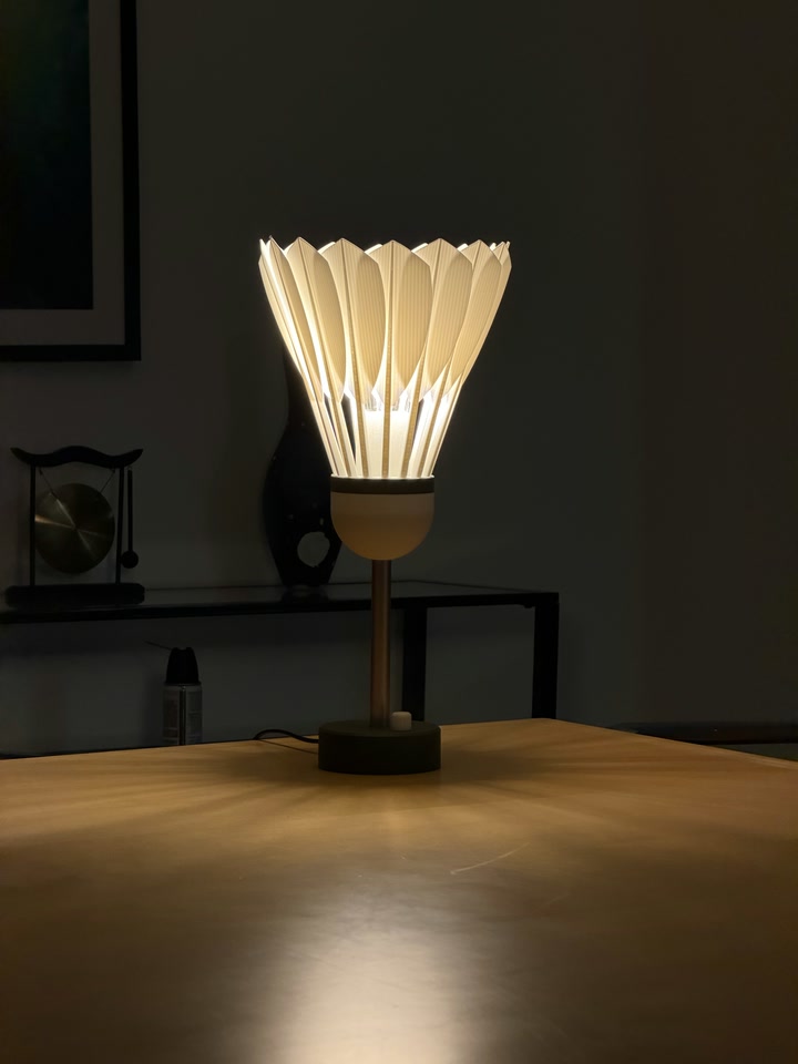 Shuttlecock Lamp casting warm light across a wooden table
