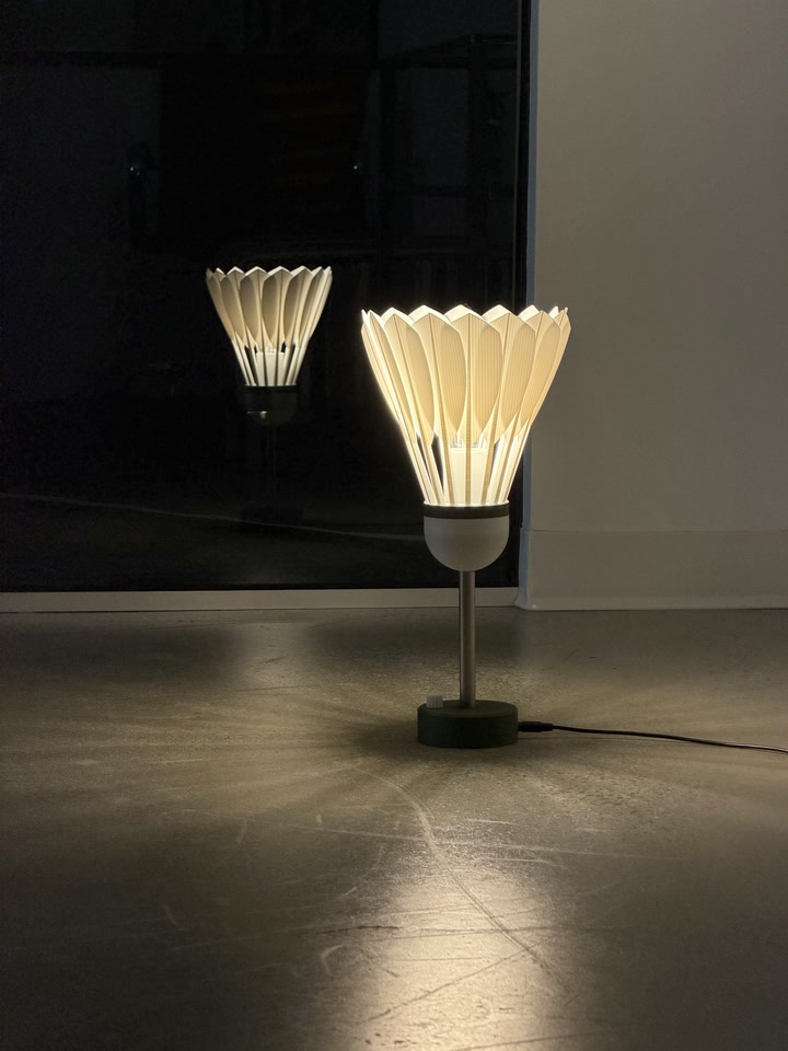 Shuttlecock Lamp glowing beside a mirror with its reflection